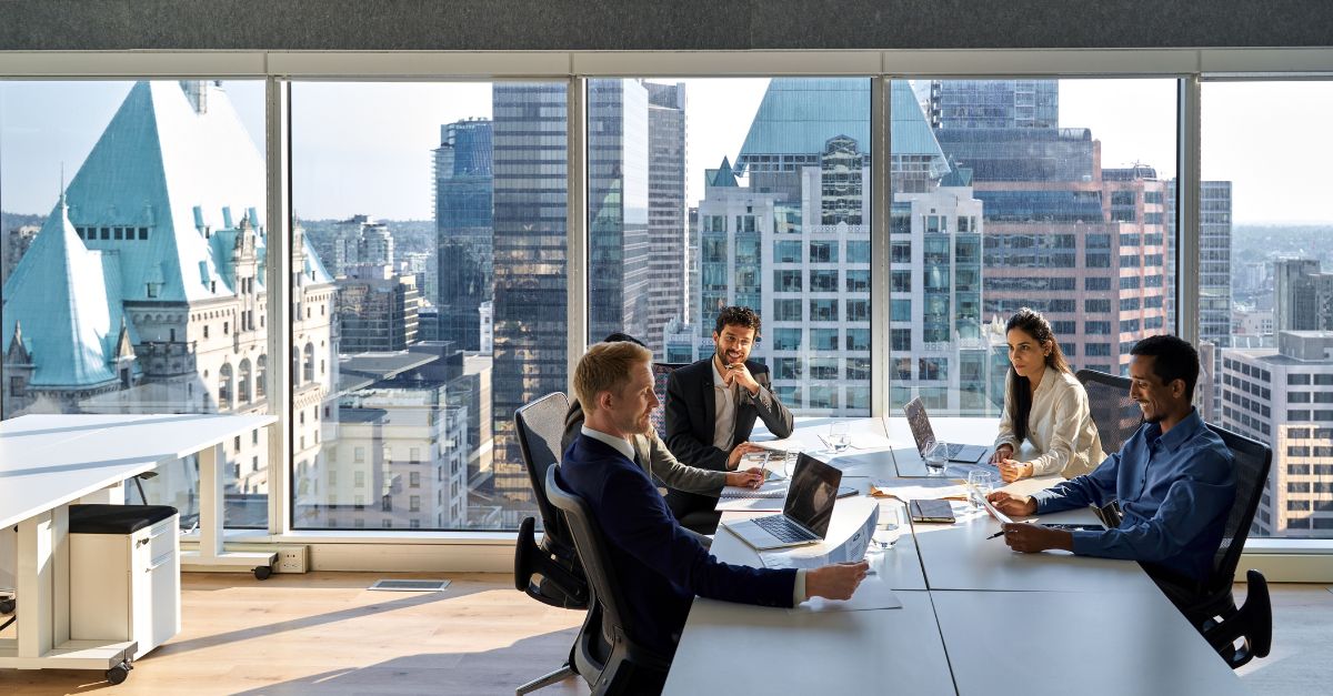 Business professionals having a meeting in a modern office with a view of the city skyline, discussing strategies related to the advantages of moving your ERP to the cloud with Microsoft Dynamics 365.